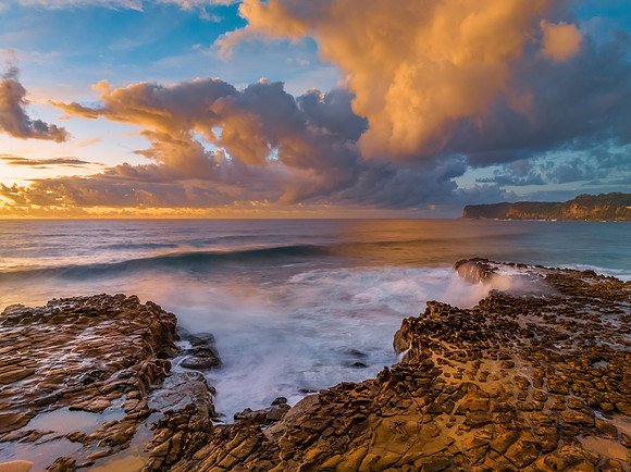 Sunrise and clouds over the ocean and rock platform