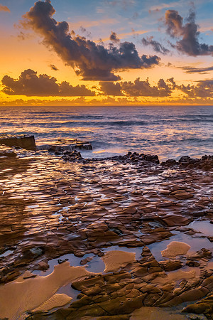 Sunrise and clouds over the ocean and rock platform