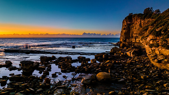 Sunrise over the sea and rocky Inlet with clear skies and a low