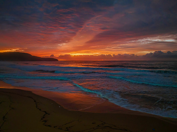 Cloud covered sunrise at the seaside in pink and blue