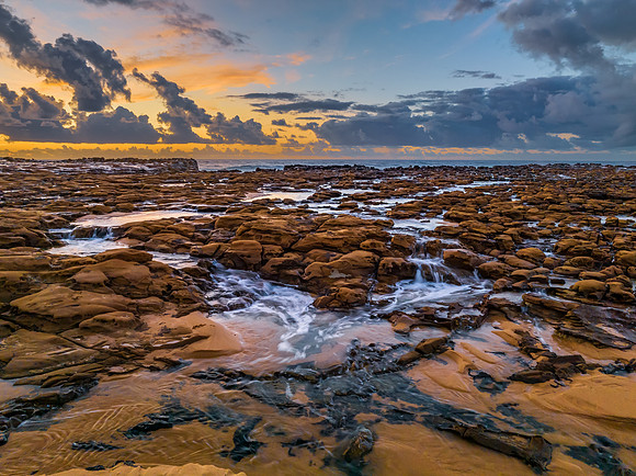 Sunrise and clouds over the ocean and rock platform
