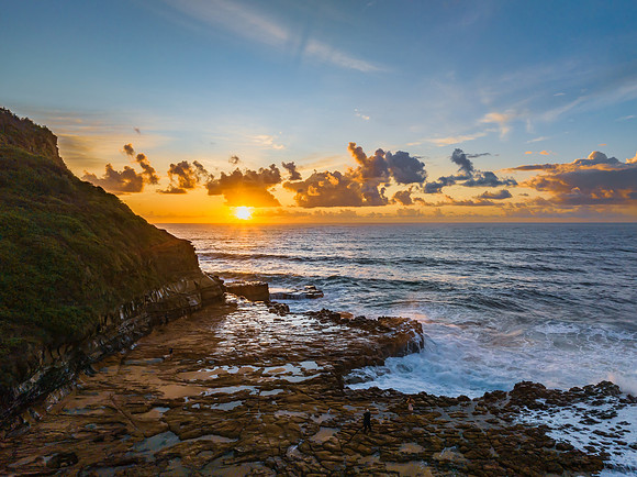 Sunrise and clouds over the ocean and rock platform