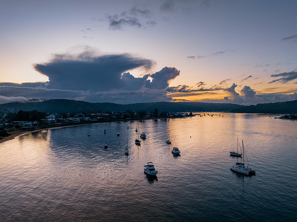 Aerial sunrise waterscape with scattered rain clouds, fog and bo