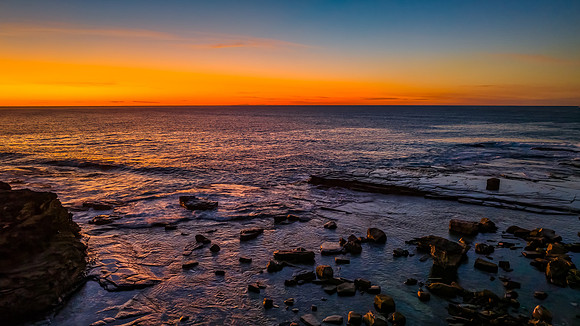 Orange Dawn over the calm sea and rocky Inlet