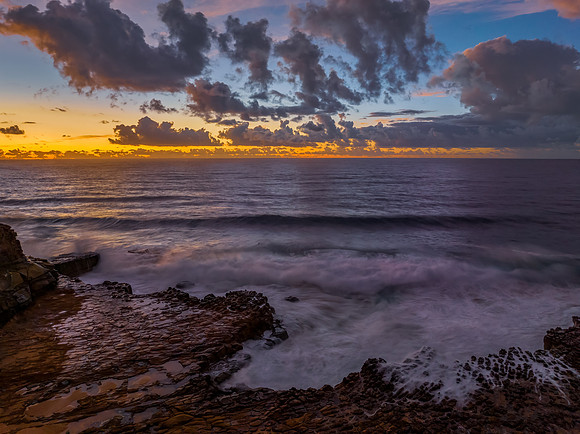 Sunrise and clouds over the ocean and rock platform