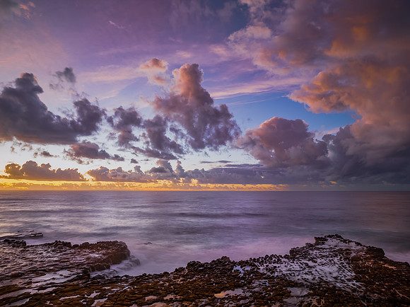 Sunrise and clouds over the ocean and rock platform