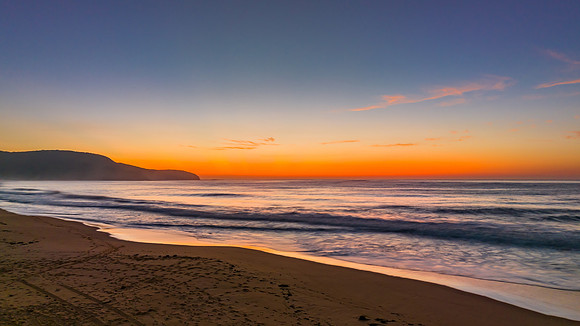 Soft hazy sunrise seascape and vibrant crepuscular rays on the h