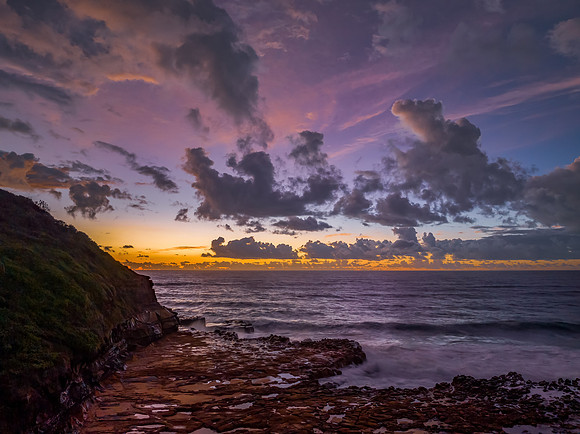 Sunrise and clouds over the ocean and rock platform