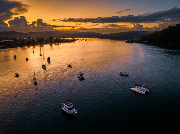 Aerial sunrise waterscape with scattered rain clouds, fog and bo