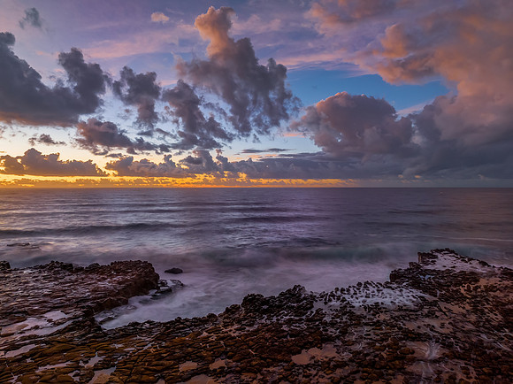 Sunrise and clouds over the ocean and rock platform