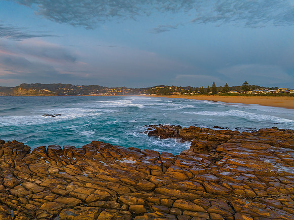 Ocean sunrise with rock platform and clouds