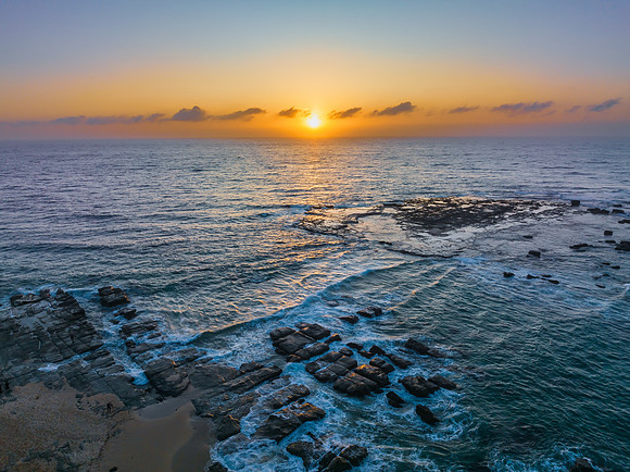 Aerial sunrise seascape with the sun, high tide and rock platfor