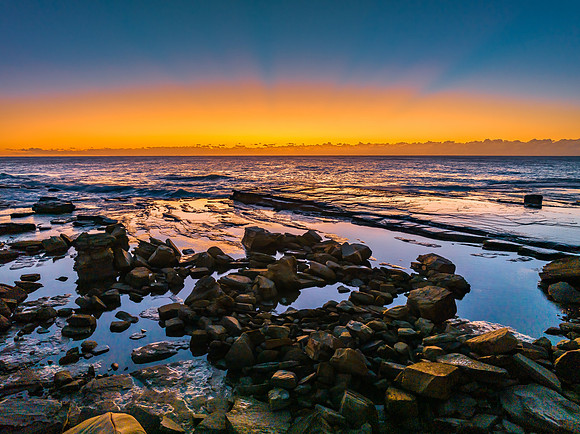 Sunrise over the sea and rocky Inlet with clear skies and a low