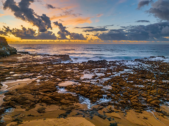 Sunrise and clouds over the ocean and rock platform