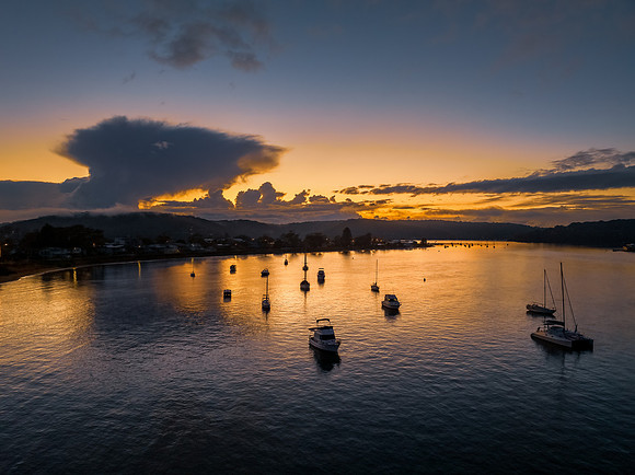 Aerial sunrise waterscape with scattered rain clouds, fog and bo