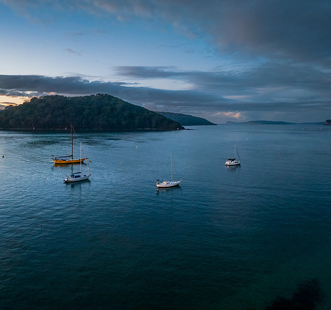 Aerial sunrise waterscape with scattered rain clouds, fog and bo