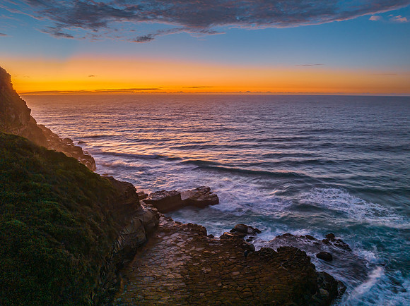 Ocean sunrise with rock platform and clouds