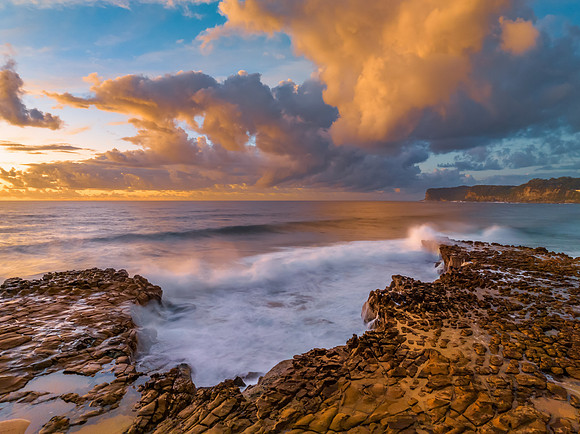 Sunrise and clouds over the ocean and rock platform