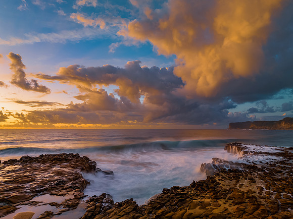 Sunrise and clouds over the ocean and rock platform