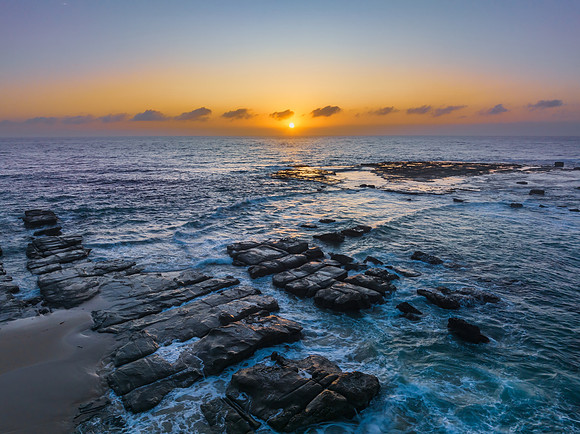 Aerial sunrise seascape with the sun, high tide and rock platfor