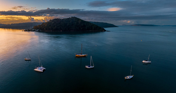 Aerial sunrise waterscape with scattered rain clouds and boats