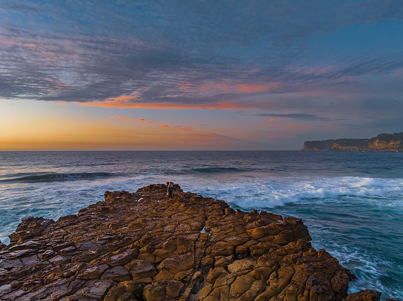 Ocean sunrise with rock platform and clouds