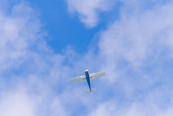 Small blue and white airplane in the blue sky