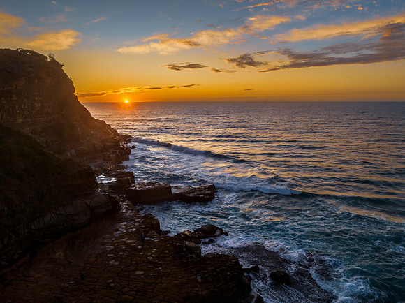 Ocean sunrise with rock platform and clouds