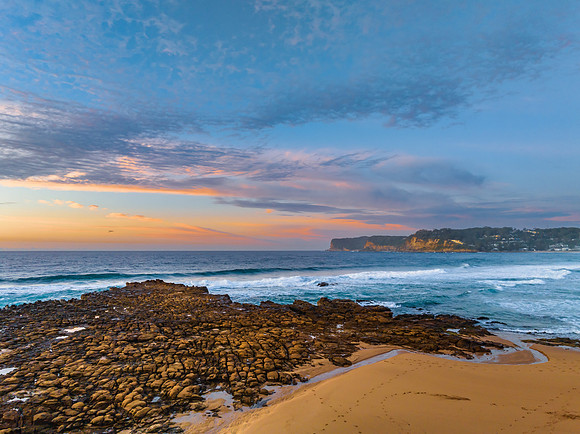 Ocean sunrise with rock platform and clouds