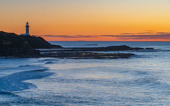 Sunrise seascape with lighthouse in the distance