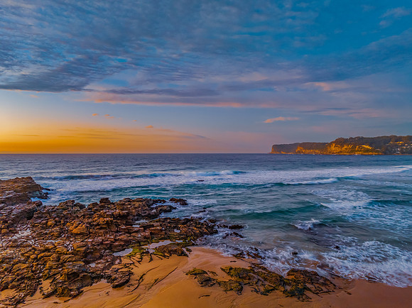 Ocean sunrise with rock platform and clouds