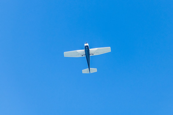 Small blue and white airplane in the blue sky