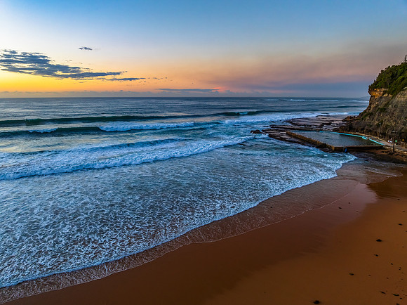 Sunrise at the beach with waves and a smattering of clouds