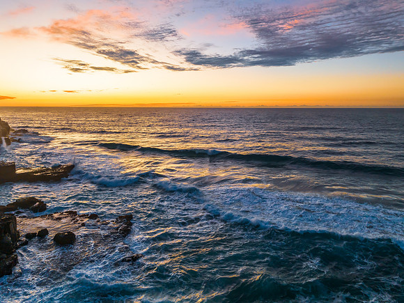 Ocean sunrise with rock platform and clouds