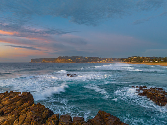 Ocean sunrise with rock platform and clouds
