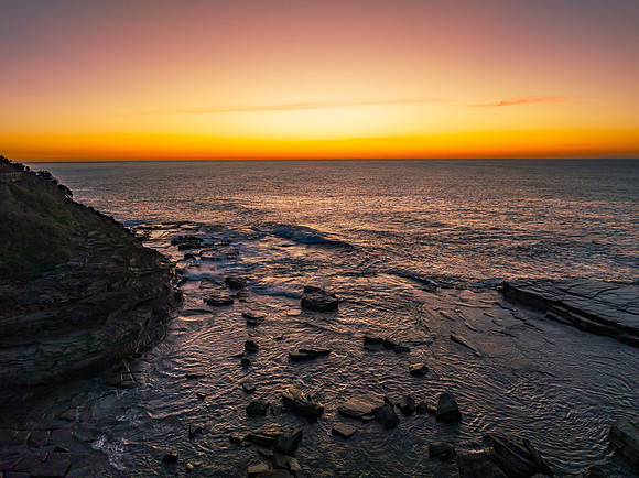 Sunrise over the calm sea and rocky Inlet