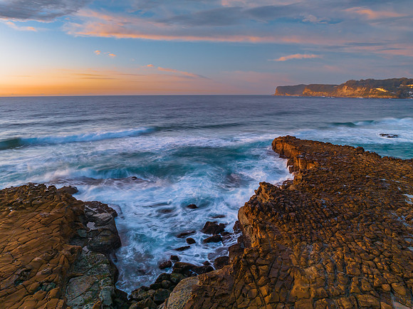 Ocean sunrise with rock platform and clouds