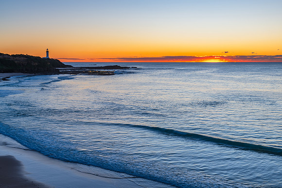 Sunrise seascape with lighthouse in the distance
