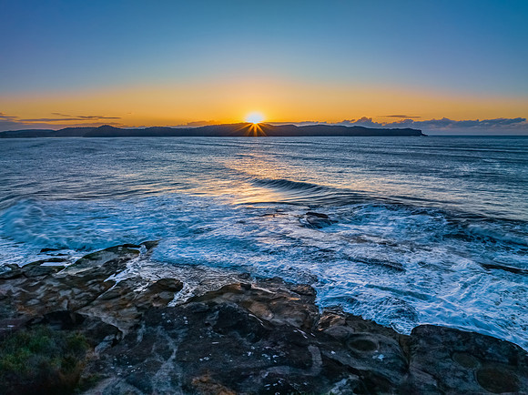 Aerial sunrise over the sea from the headland