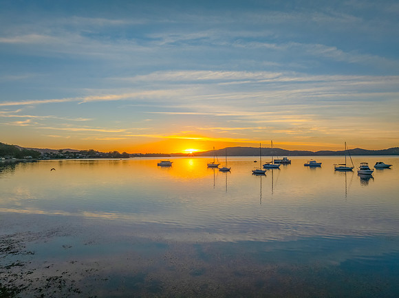 Sunrise with high cloud, boats and reflections over the water