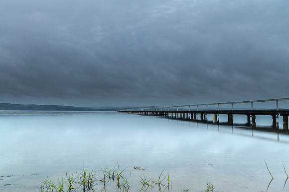 Rainy day sunrise waterscape with wharf