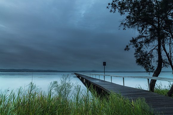 Rainy day sunrise waterscape with wharf