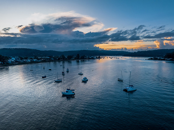 Aerial sunrise waterscape with scattered rain clouds, fog and bo