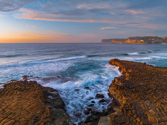 Ocean sunrise with rock platform and clouds
