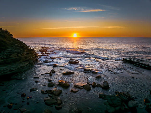 Sunrise over the calm sea and rocky Inlet
