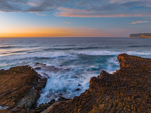 Ocean sunrise with rock platform and clouds