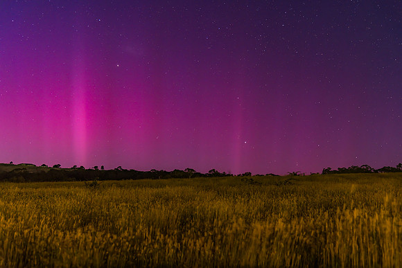 Aurora Australis display lights up the predawn sky in pinks