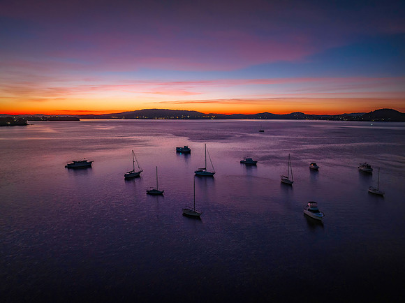 Colours of Dawn over the bay with boats and high cloud