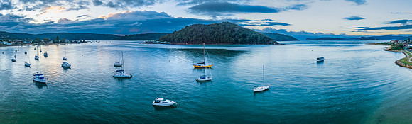 Aerial sunrise waterscape with boats and scattered rain clouds