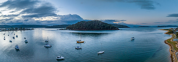 Aerial sunrise waterscape with boats and scattered rain clouds